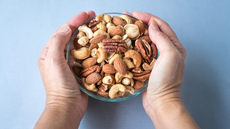 Hand holding a bowl of nuts.