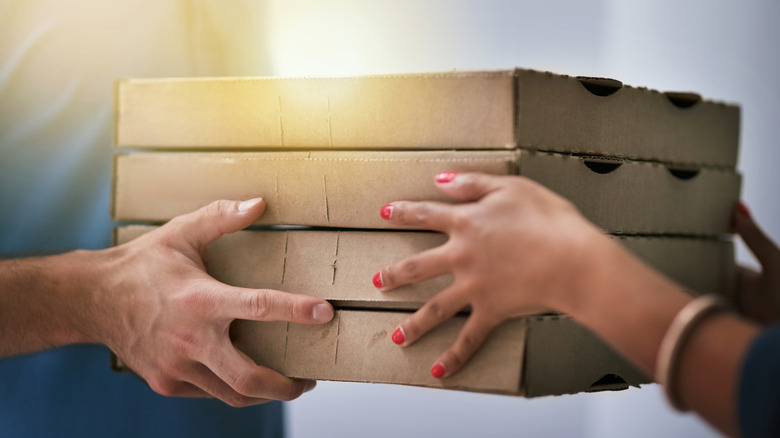 A zoomed in image of four pizza boxes being delivered to a customer.