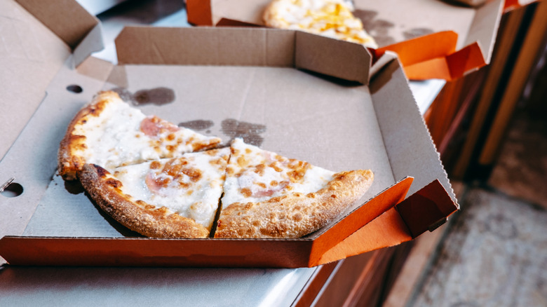 Three slices of pizza left in a box on the kitchen counter.