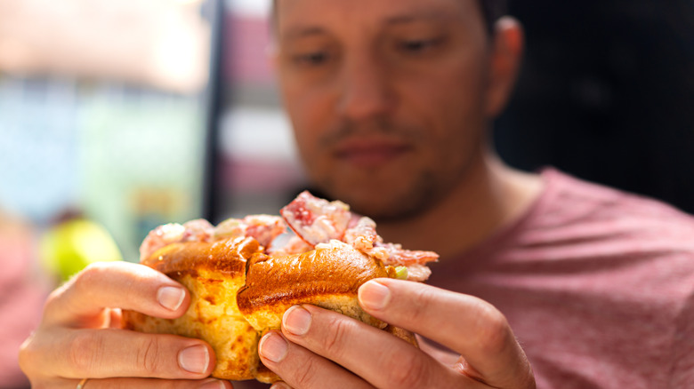 Man holding a lobster roll sandwich