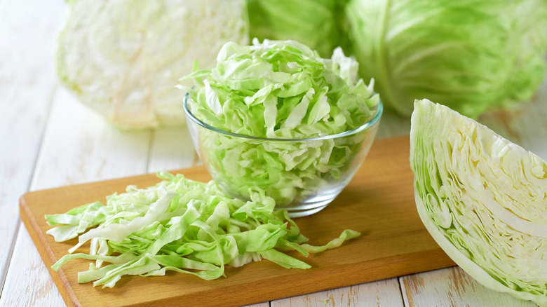 Sliced and wedged green salad on a cutting board and in bowl