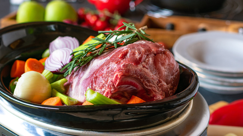 Raw roast in a slow cooker with vegetables