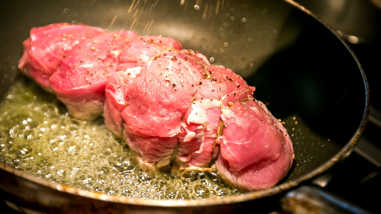 Raw roast searing in a hot frying pan of oil