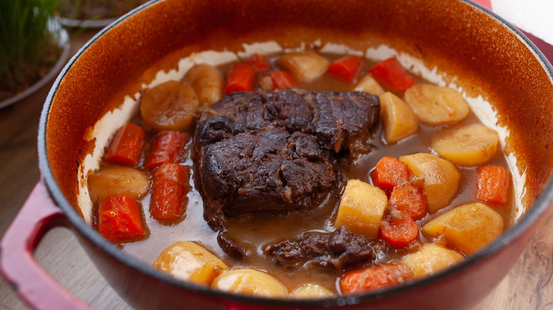 Close-up of pot roast with vegetables in braising liquid in a pot