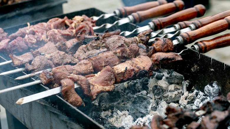 Barbecue meat on skewers over coals