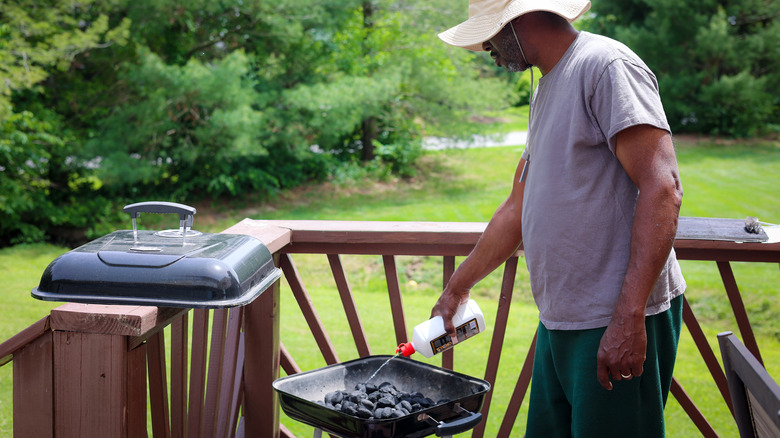 Man using lighter fluid on a grill