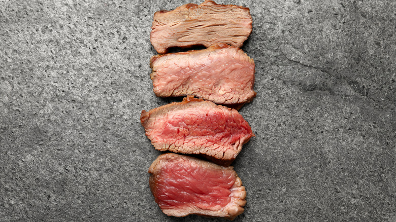 Four slices of steak ranging from rare at the bottom to well-done at the top