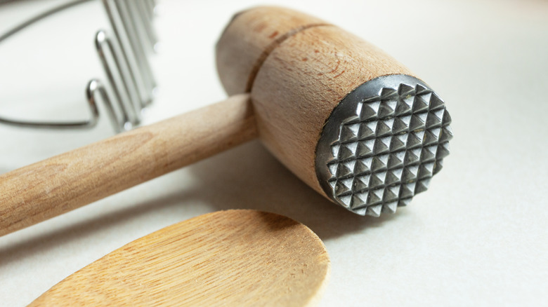A wooden meat mallet on a white background