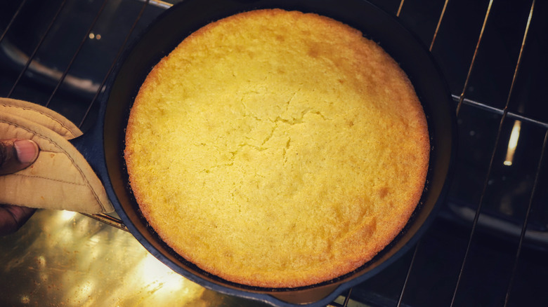 Hand taking cornbread out of oven