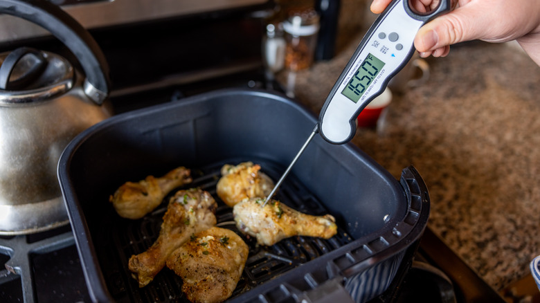 person sticking a meat thermometer into air fried chicken