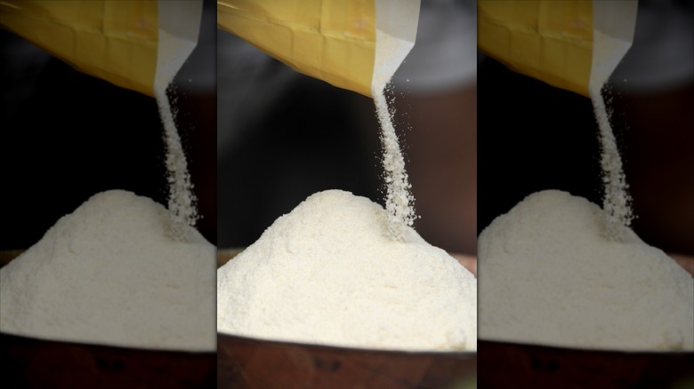 A heap of flour being poured from a paper bag.