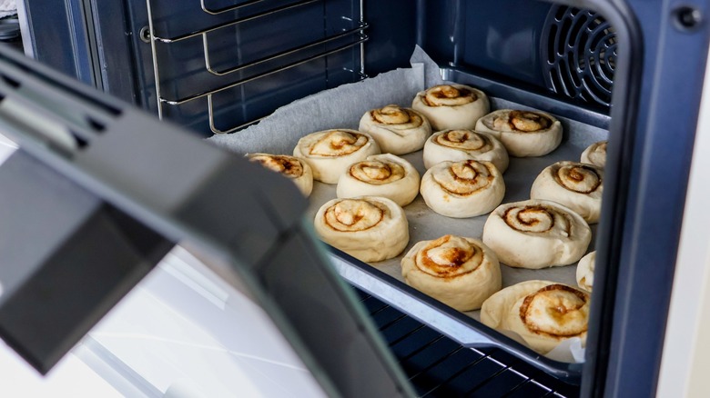 Cinnamon rolls on a baking sheet, inside an oven.