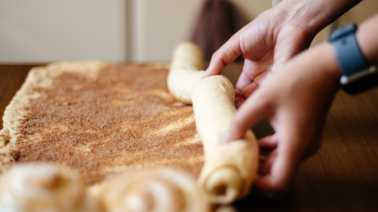 Dough being rolled with a cinnamon filling.