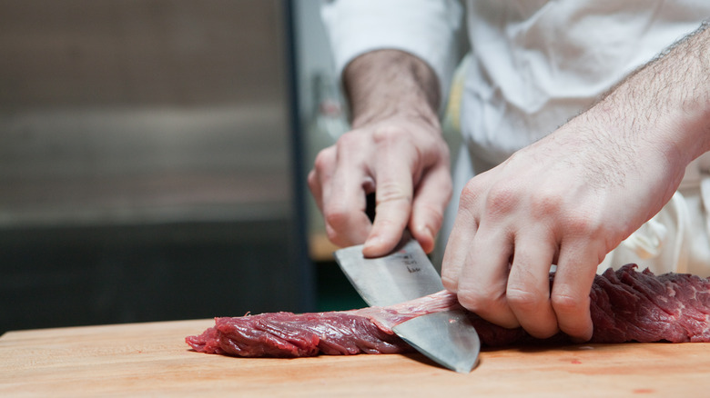 Person slicing beef with a sharp knife
