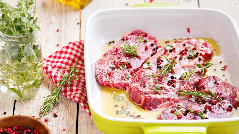 Cuts of raw beef marinading in herbs and spices