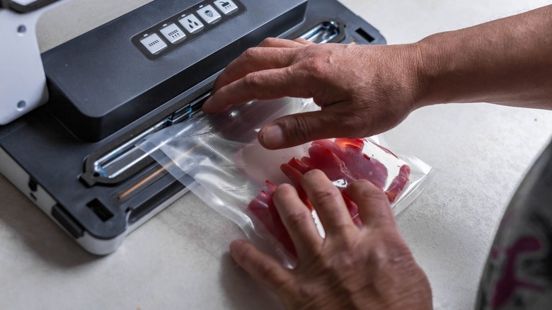A man vacuum sealing meat for storage