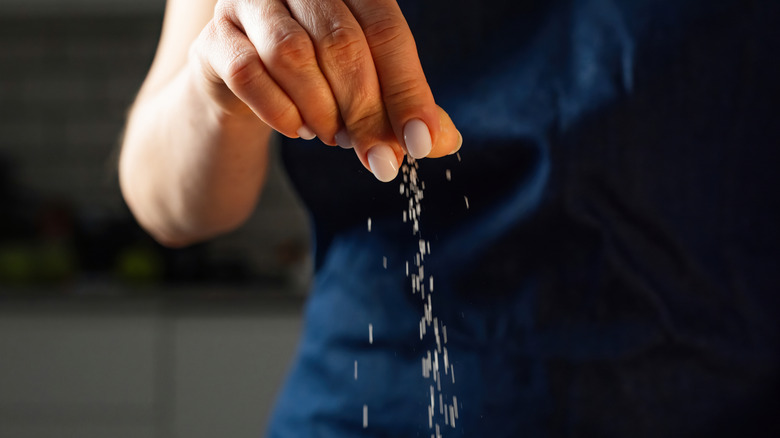 A woman adding a pinch of salt