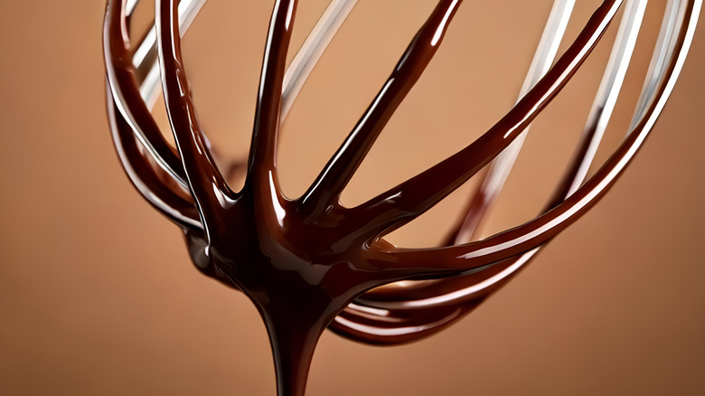 A metal whisk with melted chocolate