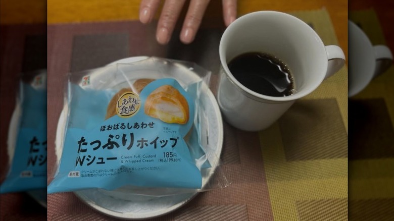 A 7-Eleven cream puff next to a cup of coffee.