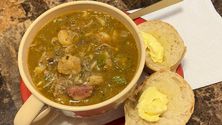 Bowl of coastal seafood gumbo with side of split and buttered dinner roll