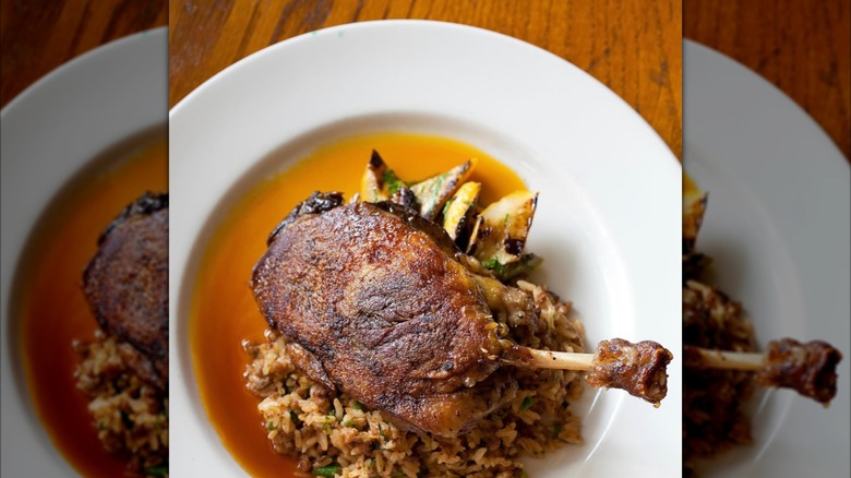 Duck confit on a white plate with rice at Herbsaint