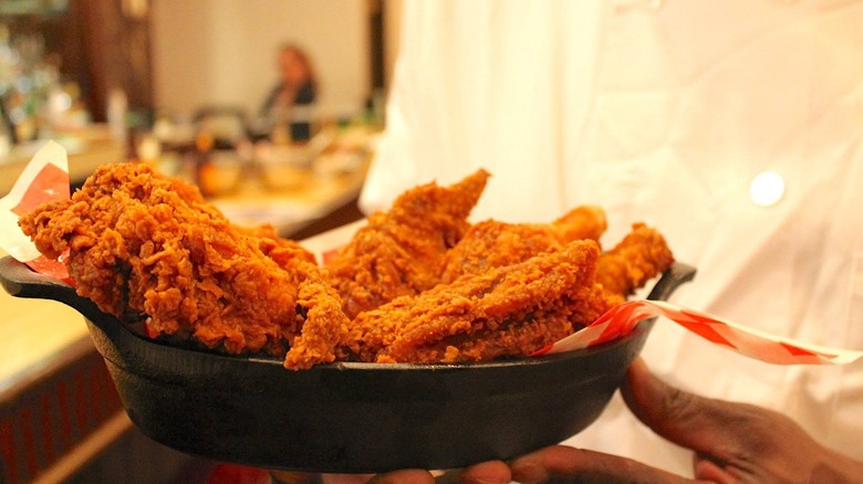 Chef holding fried chicken in skillet