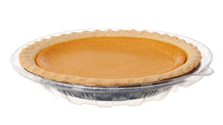 A sweet potato pie in a foil pie plate enclosed in clear plastic packaging