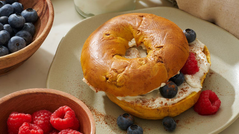 A Sam's Club French Toast Bagel on a plate with cream cheese and berries.