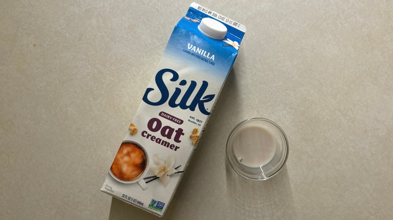 Silk Oat Vanilla Dairy-Free Creamer carton and creamer in glass ramekin on countertop