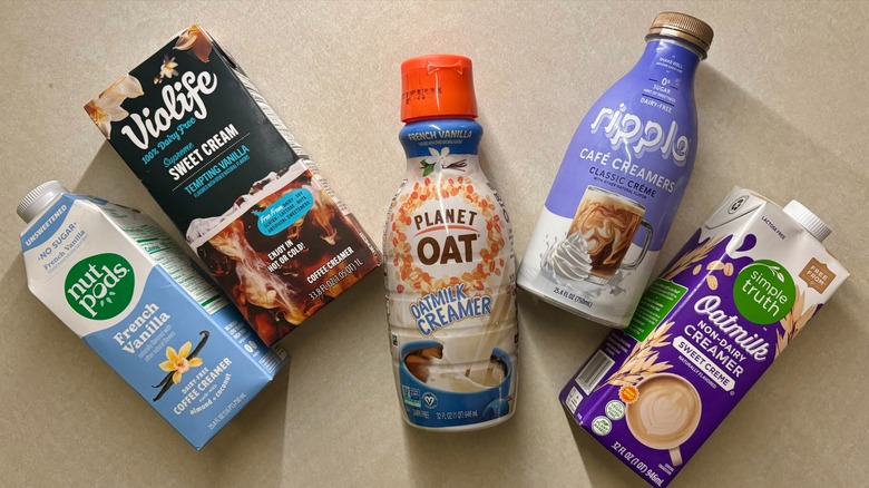 non-dairy creamer bottles on counter, including brands like planet oat and nut pods
