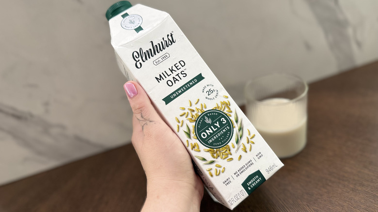 Hand holding a carton of Elmhurst oat milk