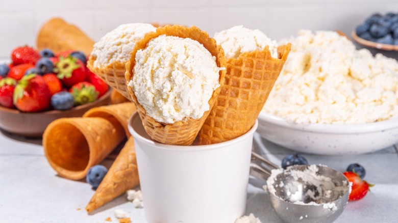Cottage cheese ice cream, trendy white cottage cheese vanilla ice cream scoops in waffle cones, with fresh berries and toppings