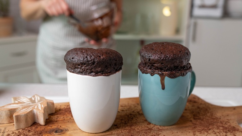 Fresh baked microwave mug cakes served by a woman with apron in the kitchen
