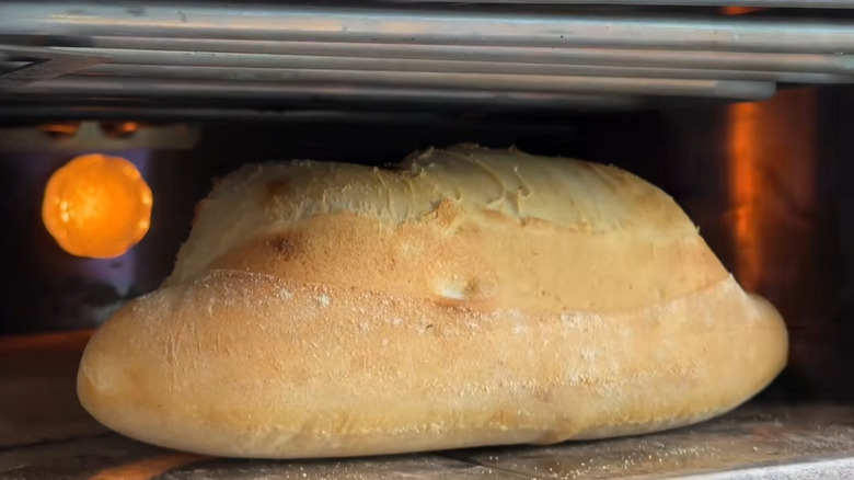 A loaf of bread made from pizza dough rests in an oven.
