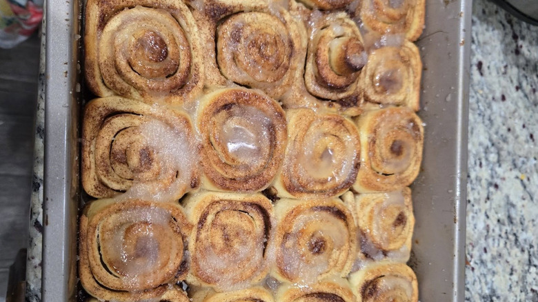 Four rows of cinnamon rolls created from left over pizza dough rest in a pan.