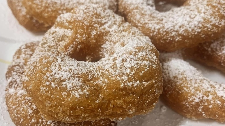 A pile of donuts created from leftover pizza dough sprinkled with icing sugar.