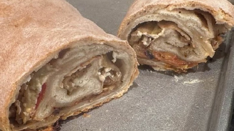 Two pieces of strudel created from leftover pizza dough rest on a metal pan.