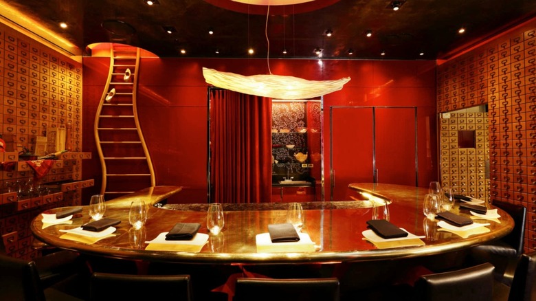 The red and gold interior of é by José Andrés in Las Vegas, with the chef's counter set for seven