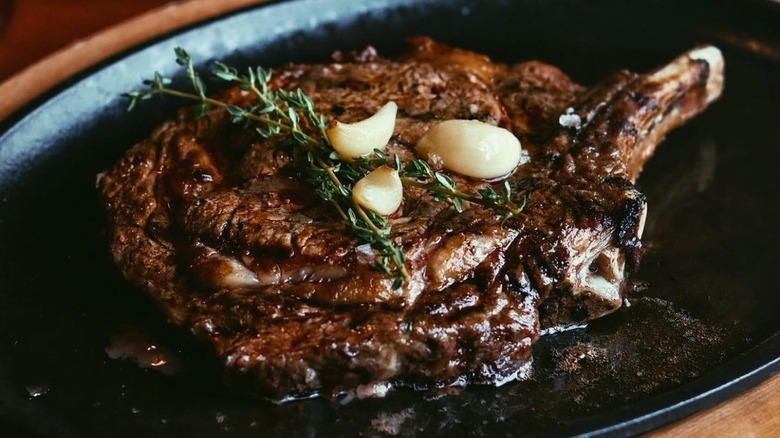 Claim Jumper Steakhouse and Bar's Bone-In Ribeye in a skillet topped with garlic and rosemary.