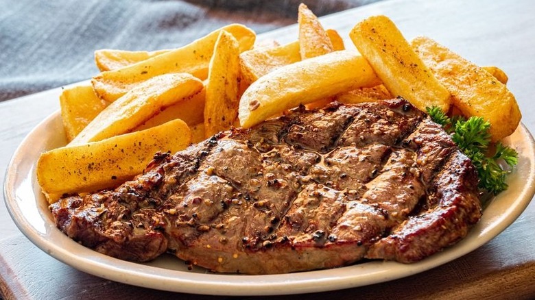 A piece of seasoned ribeye from Ponderosa Steakhouse served with french fries.
