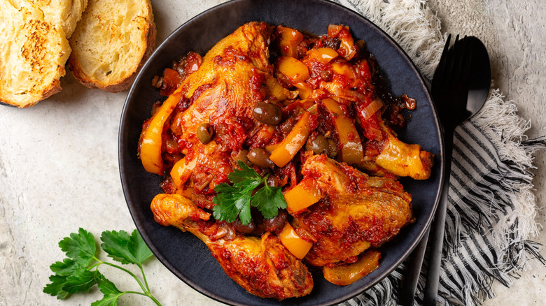 Chicken cacciatore on a black plate with a spoon