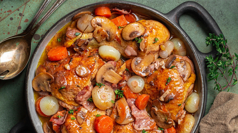 Coq au vin in a black bowl with a spoon