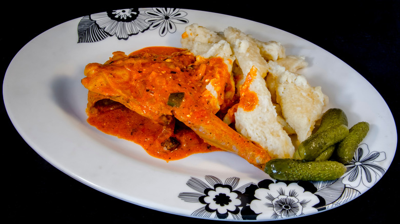 A rabbit leg and dumplings and pickles on a floral patterned plate