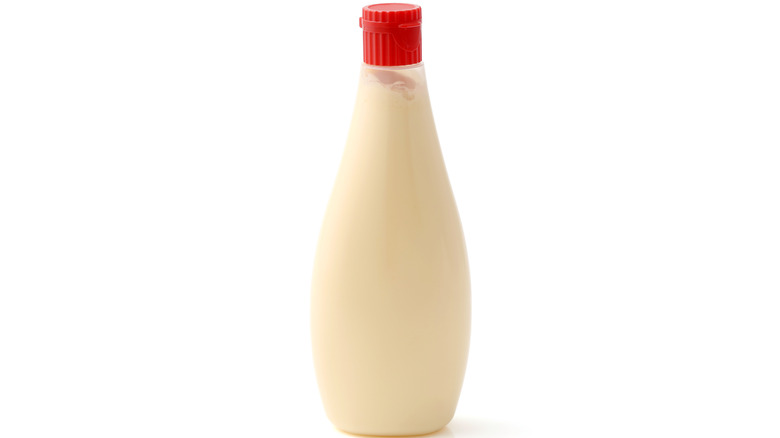 An unmarked bottle of mayonnaise on a white background
