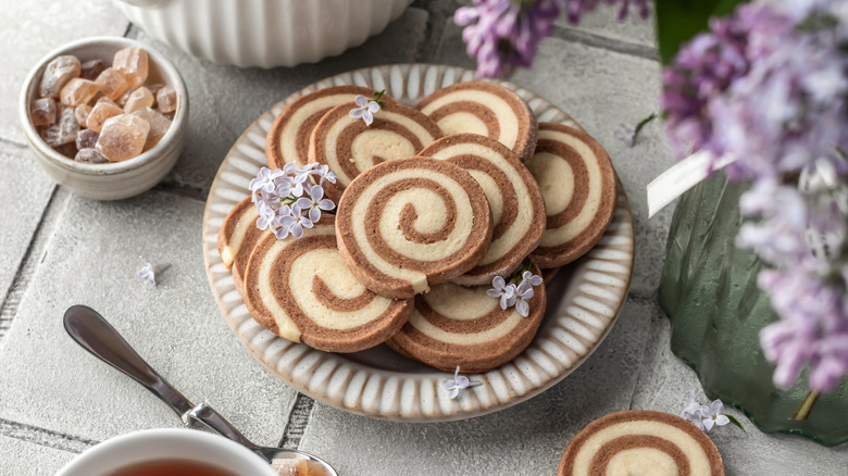 Pinwheel cookies on white plate garnished with flowers