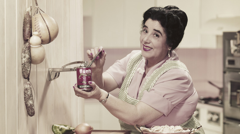 A woman uses a wall mounted can opener