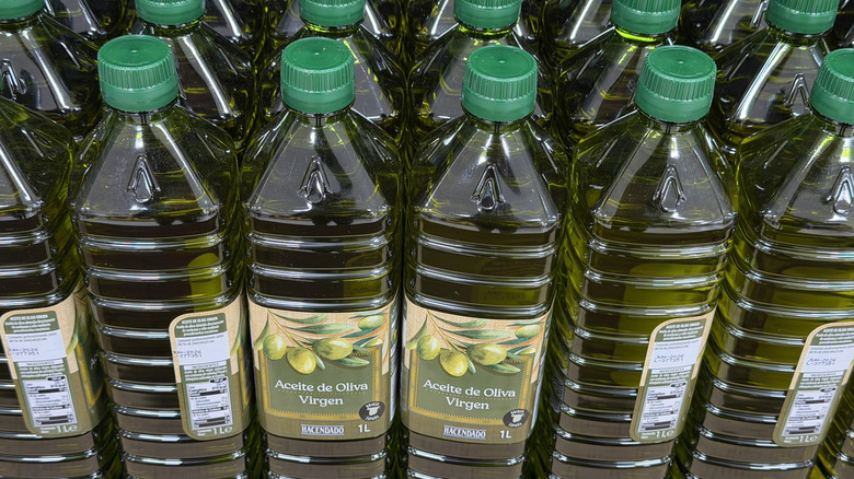Rows of clear plastic bottles filled with virgin olive oil on supermarket shelves