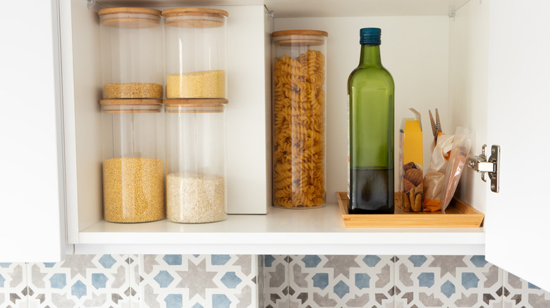 Organized kitchen pantry shelf with grains, olive oil bottle, and pasta