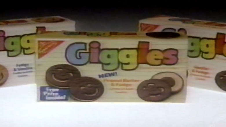 Three boxes of Giggles cookies on a white surface with black background