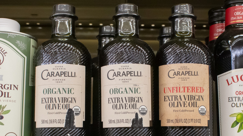 Three bottles of carapelli olive oil on display at the store with other brands of olive oils